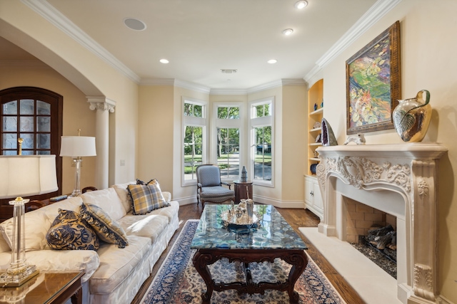 living room with hardwood / wood-style flooring, built in shelves, a high end fireplace, and ornamental molding