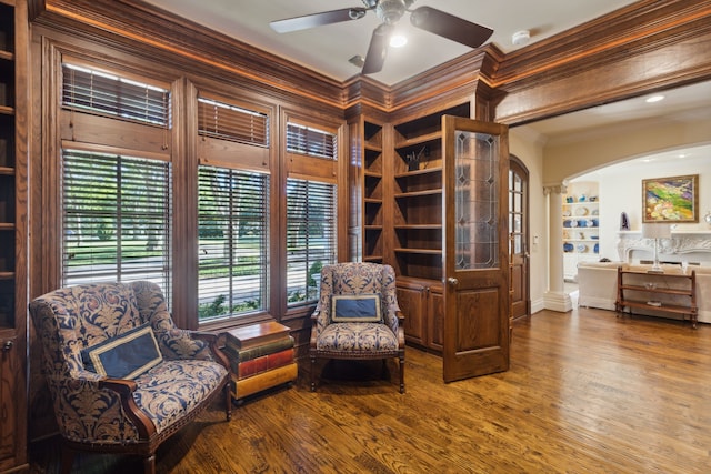 living area with wood-type flooring, a wealth of natural light, ornamental molding, and ceiling fan