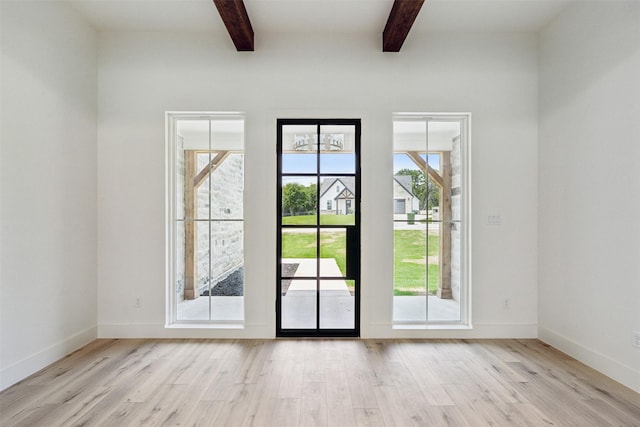 doorway with light wood-type flooring, beamed ceiling, and a healthy amount of sunlight