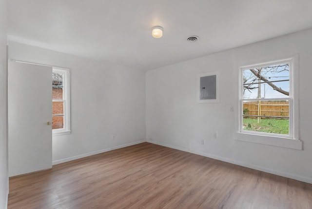 unfurnished room featuring electric panel and light hardwood / wood-style flooring