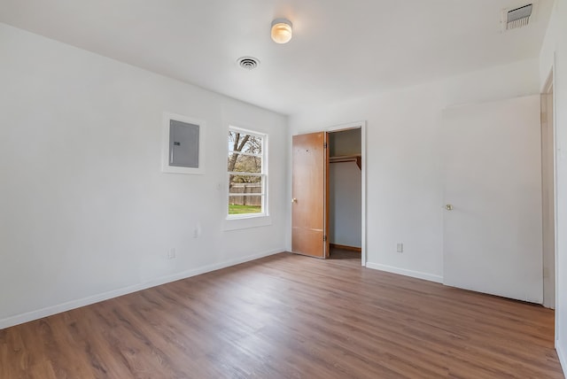 unfurnished bedroom with a closet, electric panel, and hardwood / wood-style flooring