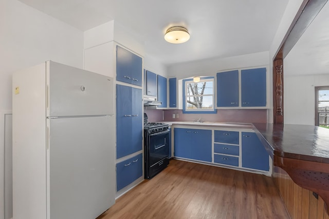 kitchen with dark wood-type flooring, blue cabinets, black gas stove, and white refrigerator