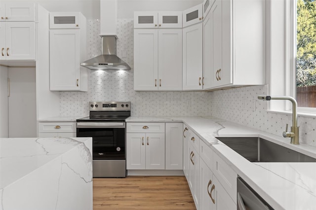 kitchen featuring sink, wall chimney range hood, stainless steel appliances, and white cabinetry