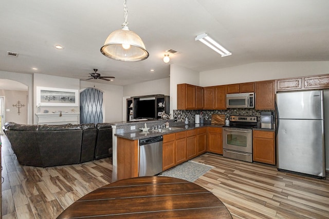 kitchen with tasteful backsplash, light hardwood / wood-style floors, pendant lighting, kitchen peninsula, and appliances with stainless steel finishes