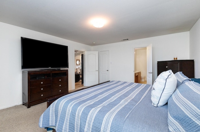 bedroom with light colored carpet and ensuite bathroom