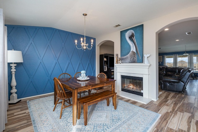 dining room featuring vaulted ceiling, an inviting chandelier, and hardwood / wood-style flooring