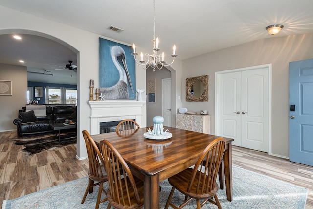 dining room featuring ceiling fan with notable chandelier and light hardwood / wood-style flooring