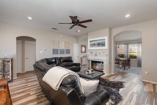 living room featuring light wood-type flooring and ceiling fan with notable chandelier