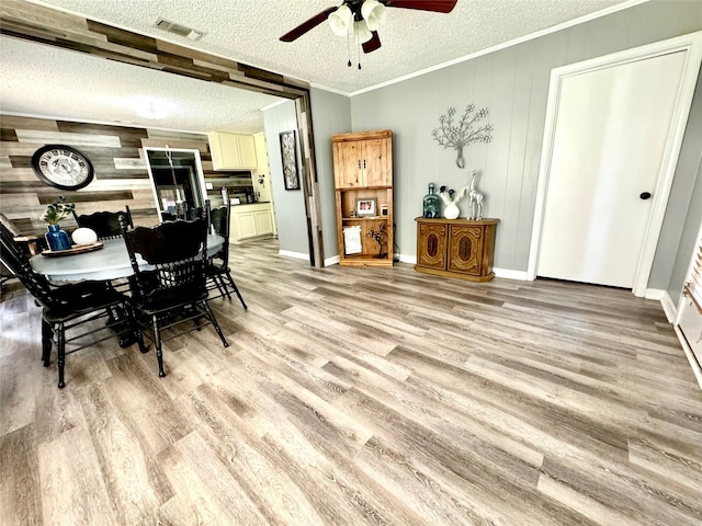 dining room with ceiling fan, a textured ceiling, light wood-type flooring, and wooden walls