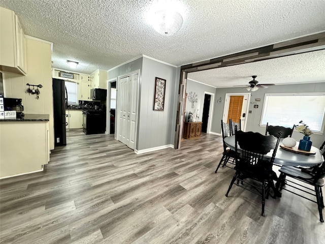 dining space with ceiling fan, a textured ceiling, ornamental molding, and light wood-type flooring