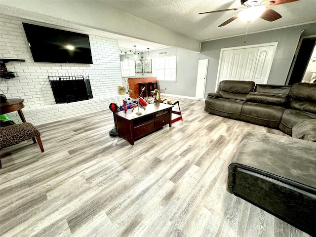 living room with light hardwood / wood-style floors, a textured ceiling, ceiling fan, and a fireplace