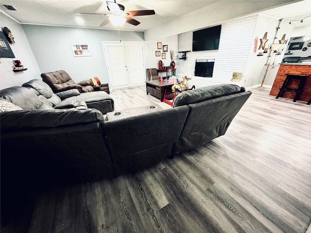 living room with hardwood / wood-style flooring, a textured ceiling, ceiling fan, and a fireplace