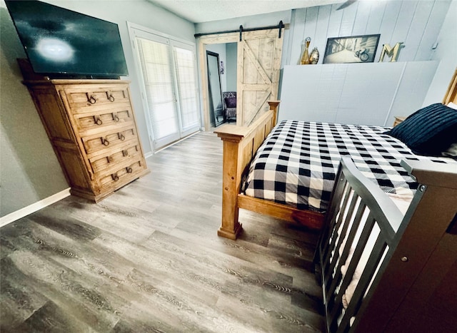 bedroom with wood-type flooring, a textured ceiling, and a barn door