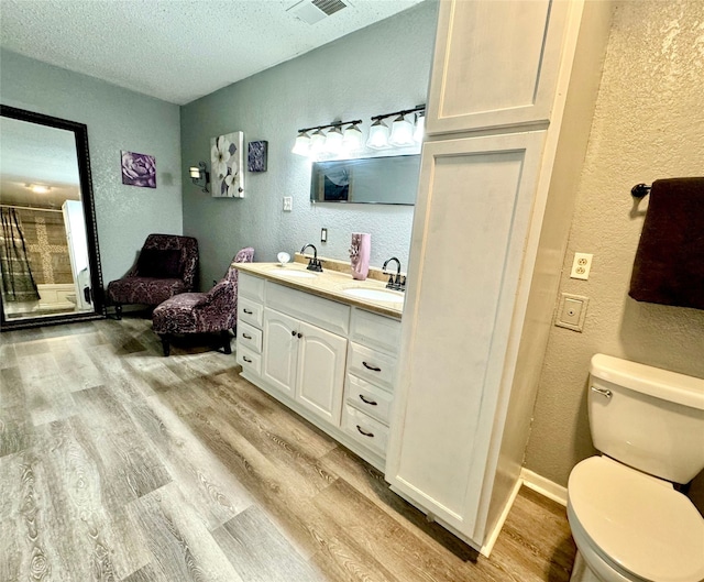 bathroom featuring toilet, vanity, wood-type flooring, and a textured ceiling