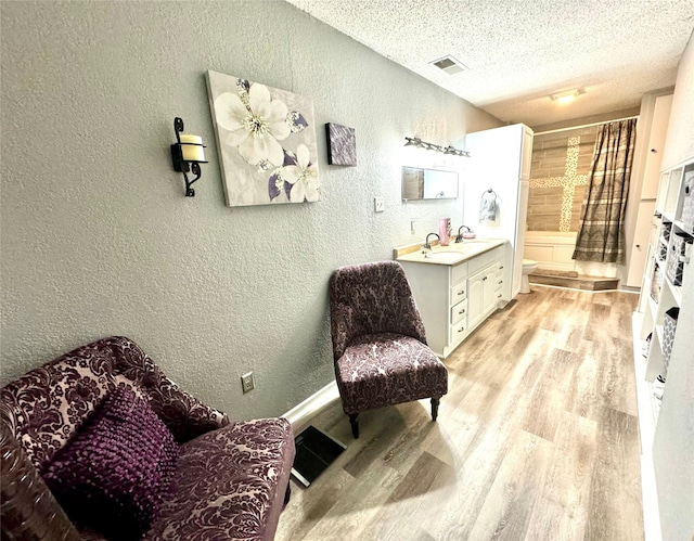 interior space featuring sink, a textured ceiling, and light hardwood / wood-style floors