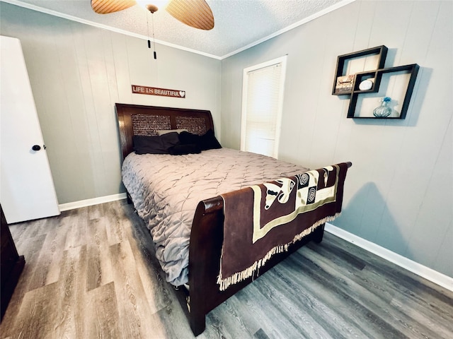 bedroom featuring ceiling fan, hardwood / wood-style floors, ornamental molding, and a textured ceiling