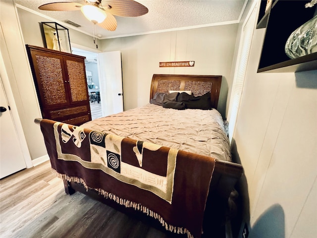 bedroom featuring a textured ceiling, ceiling fan, ornamental molding, and wood-type flooring