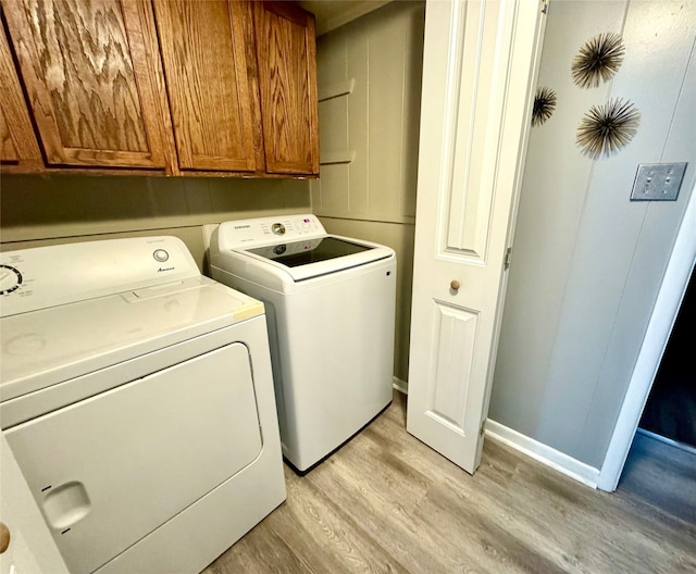 clothes washing area with cabinets, washer and dryer, and light hardwood / wood-style flooring