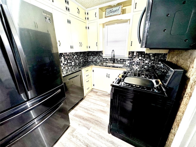 kitchen featuring white cabinets, stainless steel appliances, decorative backsplash, sink, and light hardwood / wood-style flooring