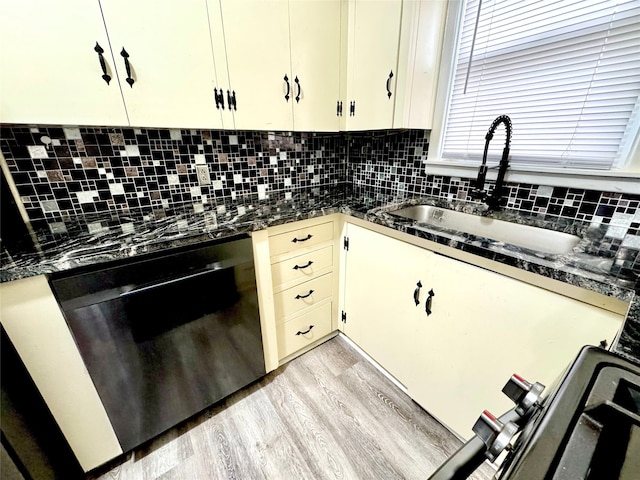 kitchen featuring black dishwasher, light hardwood / wood-style floors, sink, decorative backsplash, and cream cabinets