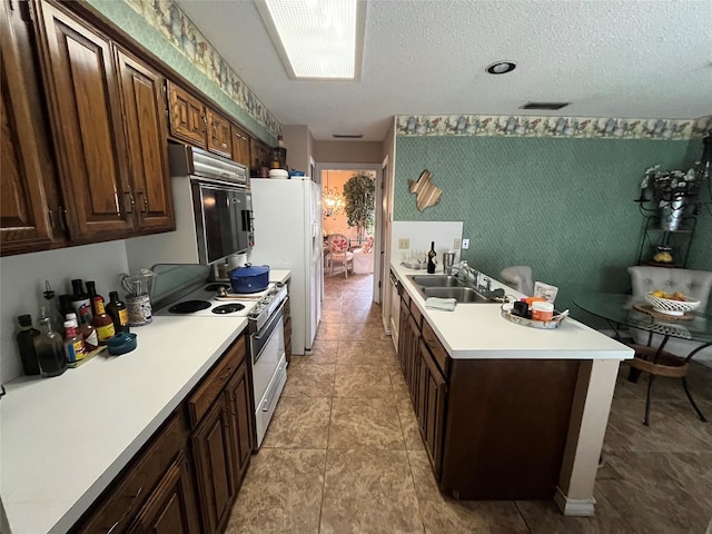 kitchen featuring white appliances, a textured ceiling, sink, light tile patterned floors, and dark brown cabinets