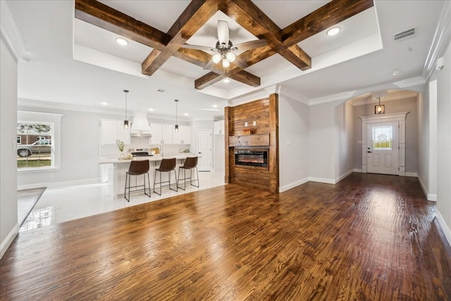 living room featuring crown molding, beam ceiling, dark hardwood / wood-style floors, a large fireplace, and coffered ceiling