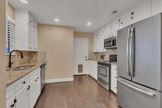 kitchen with sink, dark wood-type flooring, stainless steel appliances, white cabinets, and light stone counters