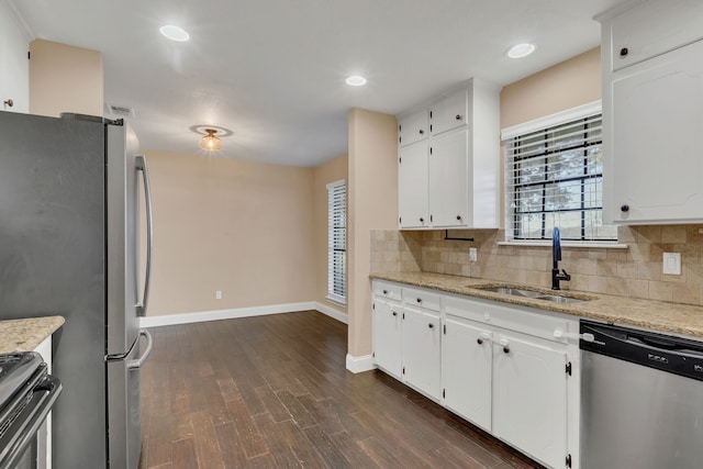 kitchen with appliances with stainless steel finishes, white cabinetry, light stone counters, and sink