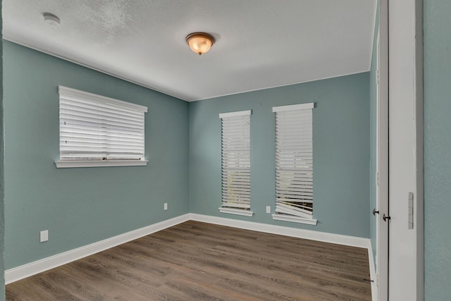 empty room with dark hardwood / wood-style floors and a textured ceiling