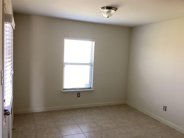 spare room featuring baseboards and light tile patterned floors