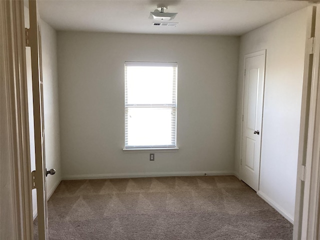 carpeted spare room featuring baseboards and visible vents