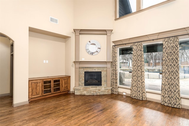 unfurnished living room featuring a fireplace, dark hardwood / wood-style floors, and a towering ceiling