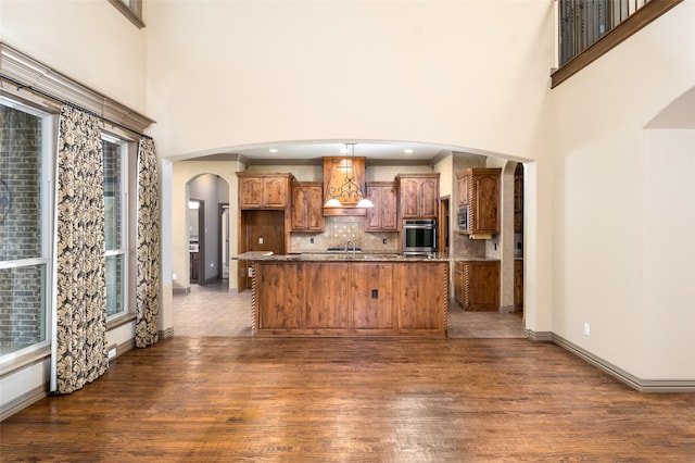 kitchen with tasteful backsplash, dark hardwood / wood-style floors, oven, and a center island