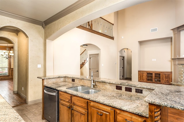 kitchen featuring stainless steel dishwasher, sink, light stone counters, and ornamental molding