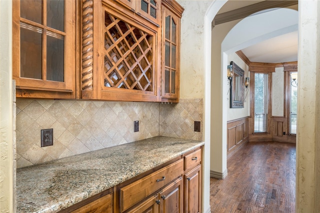 kitchen with tasteful backsplash, light stone countertops, ornamental molding, and dark hardwood / wood-style floors