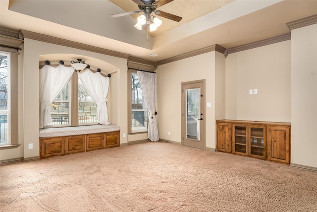 interior space featuring ceiling fan, a tray ceiling, crown molding, and carpet flooring