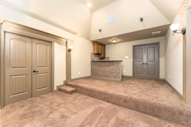 unfurnished living room with carpet floors and high vaulted ceiling