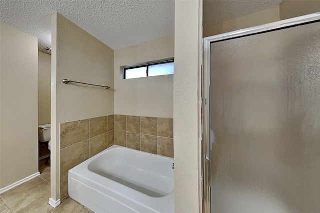 bathroom with tile patterned flooring, a textured ceiling, toilet, and plus walk in shower