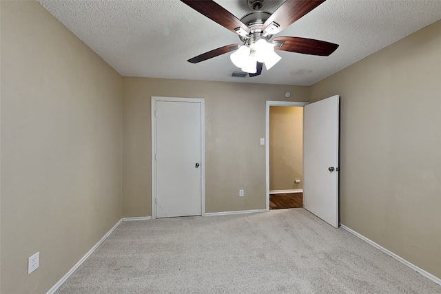 unfurnished bedroom featuring ceiling fan, a textured ceiling, and light carpet