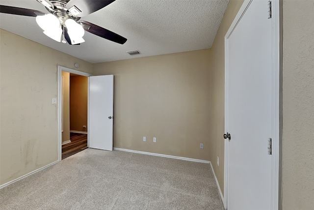 unfurnished bedroom with ceiling fan, a textured ceiling, and light carpet