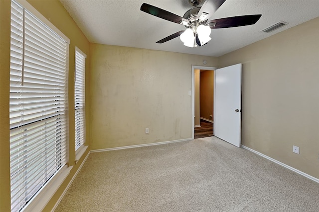 unfurnished bedroom with carpet, a textured ceiling, and ceiling fan