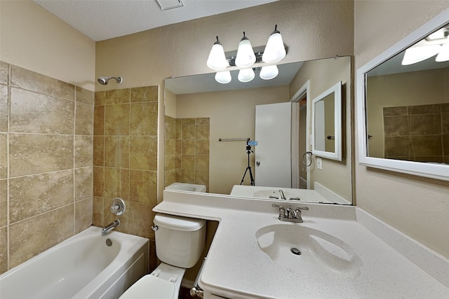 full bathroom featuring sink, toilet, a textured ceiling, and tiled shower / bath combo