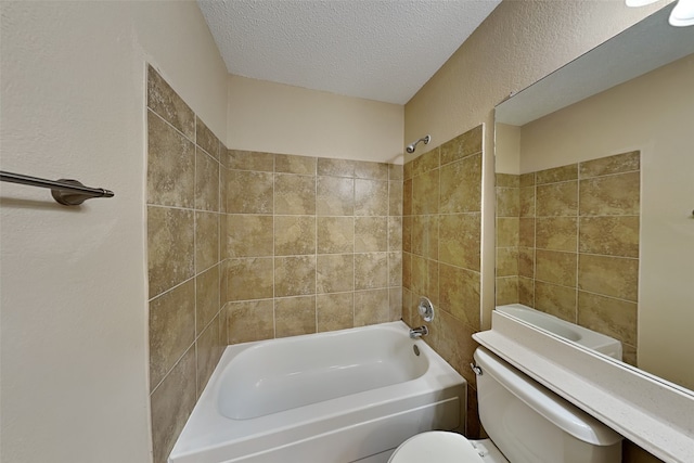 bathroom with toilet, a textured ceiling, and tiled shower / bath combo