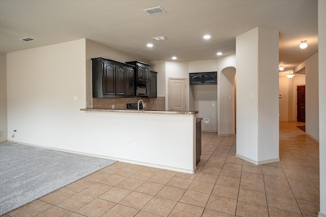 kitchen featuring decorative backsplash, sink, kitchen peninsula, and light tile patterned flooring