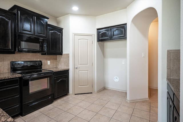 kitchen featuring backsplash, light tile patterned floors, black appliances, and dark stone counters