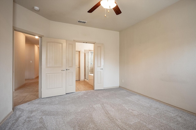 unfurnished bedroom with ceiling fan, light carpet, and ensuite bath