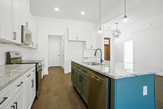 kitchen featuring decorative light fixtures, white cabinetry, stainless steel appliances, an island with sink, and sink