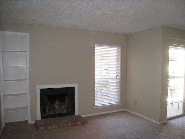 unfurnished living room featuring a textured ceiling, carpet flooring, and a fireplace