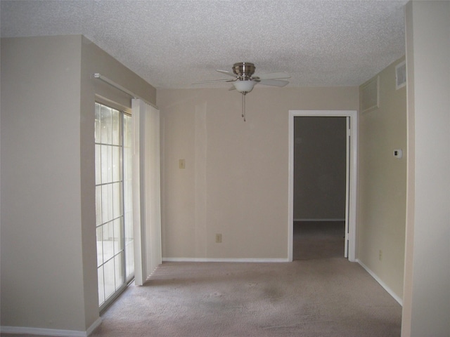 unfurnished room with a textured ceiling, ceiling fan, and light colored carpet