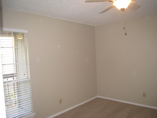 empty room with a textured ceiling, ceiling fan, and a wealth of natural light